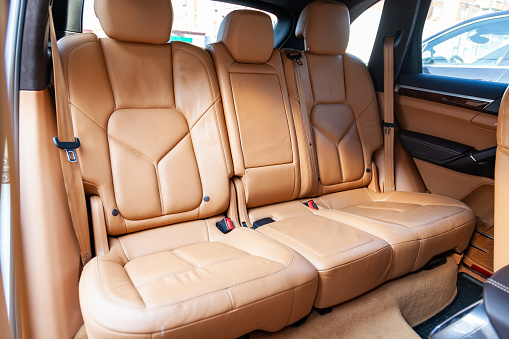 Clean after washing the rear passenger seats of matte brown or beige genuine leather inside the interior of an expensive luxury suv, preparation before selling the car.