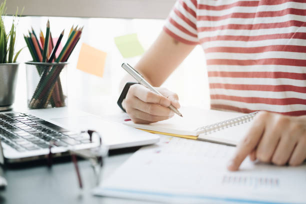 istock close up of woman's hands pointing financial report and writing in notepad. Working on project concept 1144166151