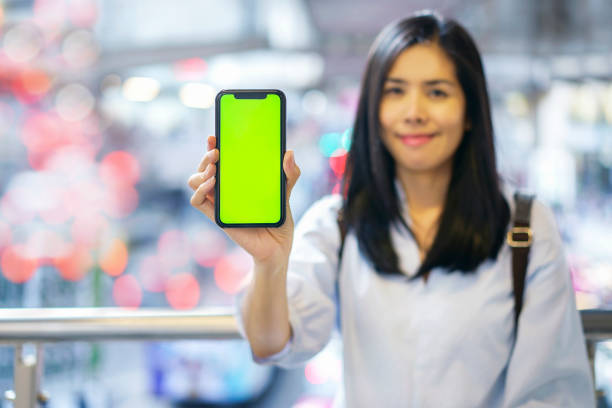 istock Woman holding smart phone blank green screen on mobile, Bokeh background. 1144169630