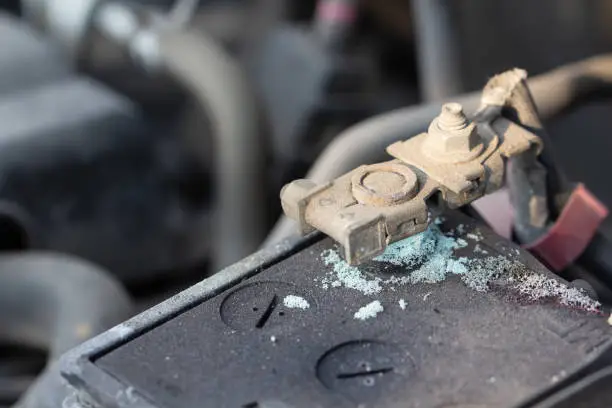 Photo of Mechanic checking car Battery terminalÂ in a garageÂ .
Old battery corrosion deteriorate leaking with blue acid powder.
Battery terminals corrode dirty damaged problem.