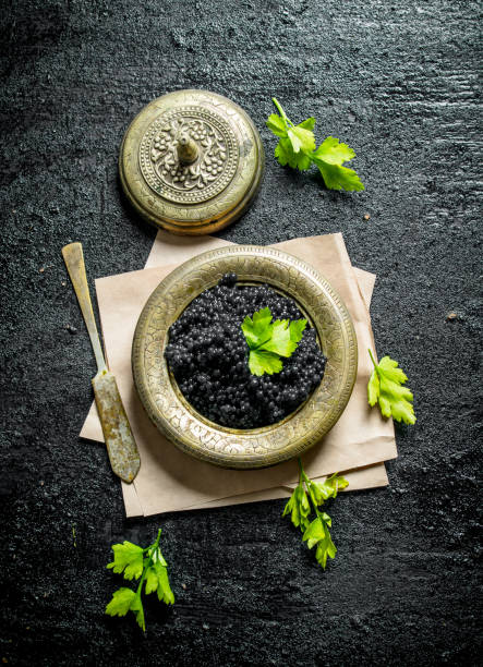 istock Black caviar in a bowl on paper with parsley. 1144171096