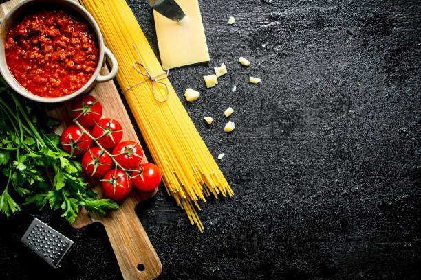 istock Bolognese sauce in a pot with dry spaghetti and cherry. 1144171134