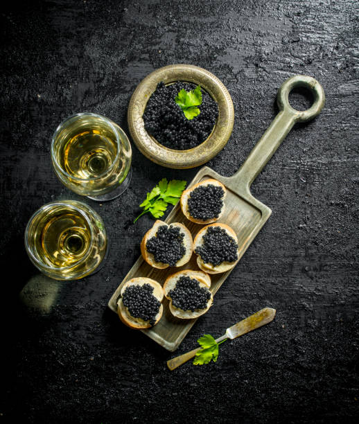 istock Black caviar on bread slices and the wine. 1144172154