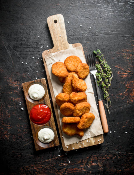 istock Chicken nuggets on a cutting Board with thyme and sauces. 1144172376