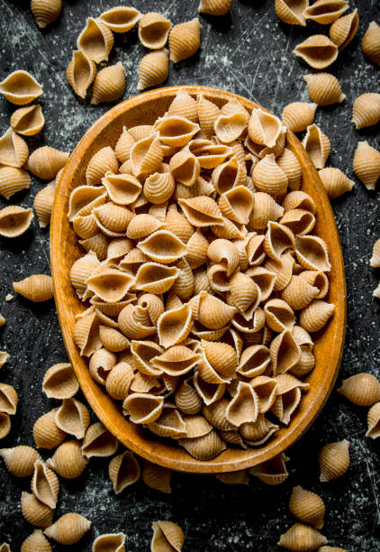 istock Pasta background. Dry pasta conchille in bowl. 1144173575