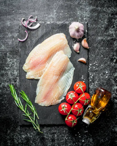 Photo of Fish fillet with rosemary,garlic and oil in the bottle.