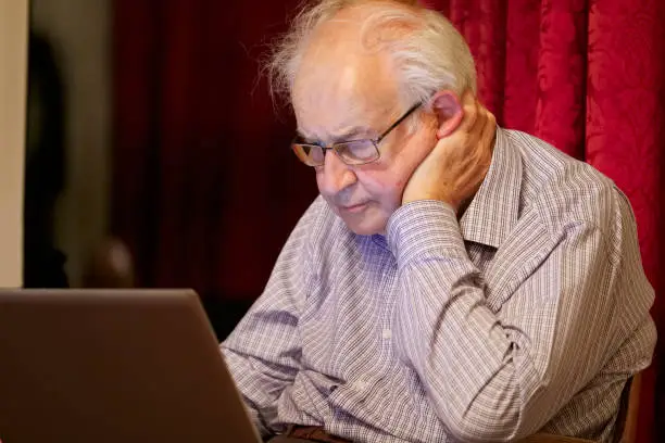 Old elderly senior person learning computer and online internet skills to prevent fraud uk