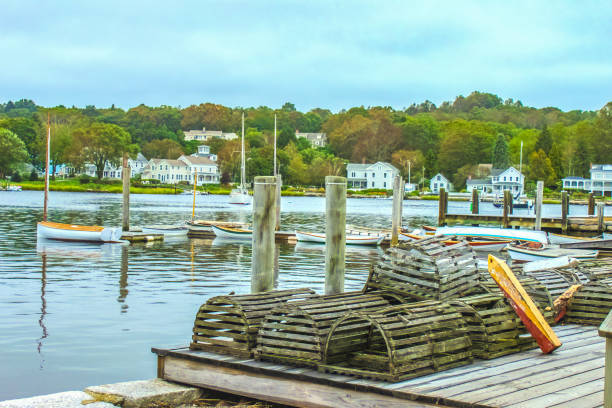 lobster-krabben-fallen stapelten sich auf der anlegestelle mit kleinen booten und segelbooten anlegen und ziemlich weiße häuser am gegenüberliegenden ufer mit baum bedeckten baum hinter - mystic connecticut nobody new england stock-fotos und bilder