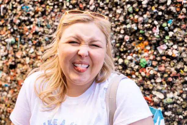 Photo of Blonde woman makes a gross face with her tongue out while visiting the Bubblegum Alley wall in San Luis Obispo California