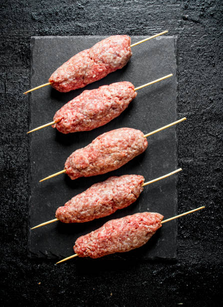 istock Raw kebab of ground beef on a black stone Board. 1144179166