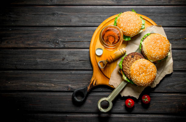 istock Burgers on paper with beer and tomatoes. 1144179196