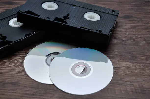 Photo of Two video cassettes isolated on a wooden background with cd's