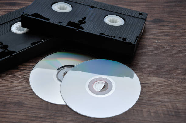 two video cassettes isolated on a wooden background with cd's - dvd obsolete cd cd rom imagens e fotografias de stock