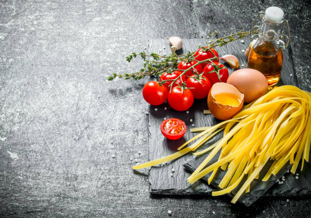 istock Home made raw pasta with thyme, eggs, oil and tomatoes. 1144187836