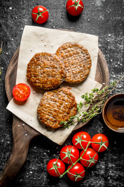 istock Cutlets on paper with thyme and tomatoes on a branch. 1144187844