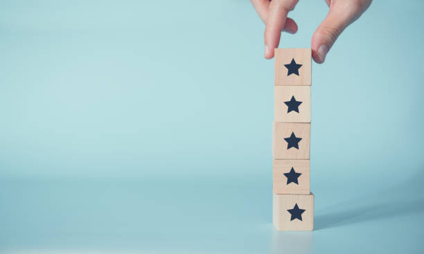 mano mujer poniendo la forma de cinco estrellas de madera sobre fondo azul. - five star fotografías e imágenes de stock