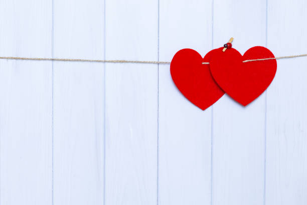 istock Two hearts hanging on a rope on woden background 1144191018