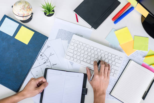 Businessman working writing business plan document and graphic designer with computer in office, top view workspace