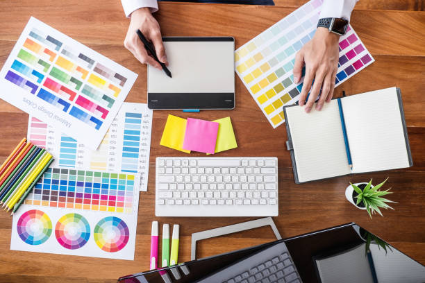istock Image of male creative graphic designer working on color selection and drawing on graphics tablet at workplace with work tools and accessories, top view 1144191129