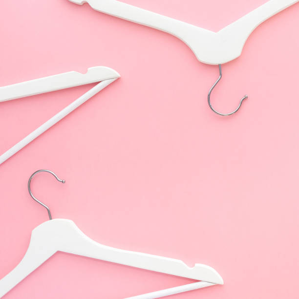 istock White hangers on pastel pink background 1144198099