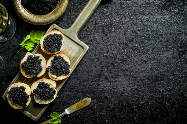 sandwiches mit schwarzem kaviar auf dem schneidebrett. - kaviar fotos stock-fotos und bilder