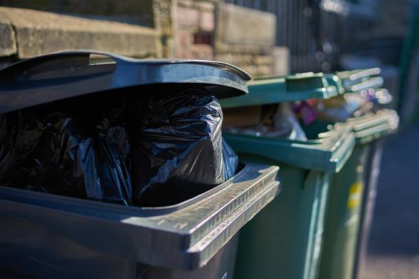 Overfull garbage cans wheelie bins close up Gray and green garbage cans overfilled with domestic refuse bin stock pictures, royalty-free photos & images