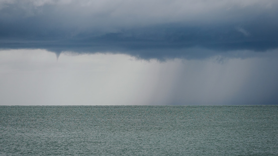Seascape with rain in the distance. Thick clouds over the sea.