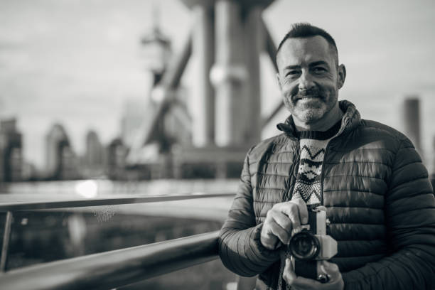 Mature man enjoys in his hobby Portrait of one handsome, senior man standing outdoors and photographing with digital camera. black and white portrait photographers stock pictures, royalty-free photos & images