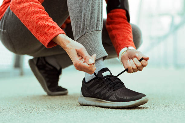 неузнаваемый старший человек, завязыв шнурки на спортивных кроссовках - senior adult shoelace human leg leg стоковые фото и изображения