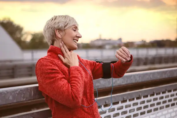 Photo of Athletic senior woman using smart watch ,checking a pulse pace
