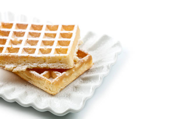 Belgium waffers with sugar powder on ceramic plate isolated on white background. Fresh baked wafers. With copy space.