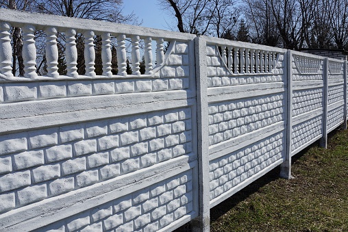 private long white concrete fence outside in green grass