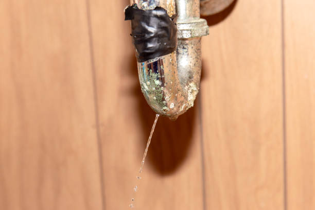 horizontal close up image of water running out of a rusted and broken  sink drain pipe taped up with duck tape.