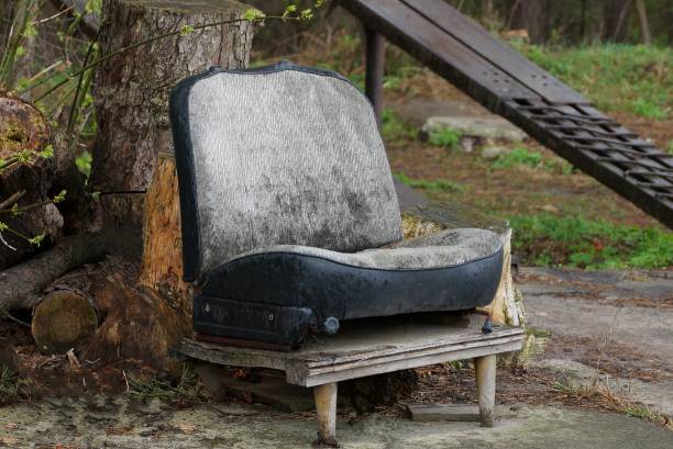 one big old gray and dirty car seat is standing outside
