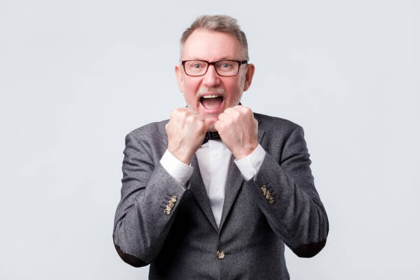 istock Happy winner. Senior handsome man in suit and glasses gesturing 1144214908
