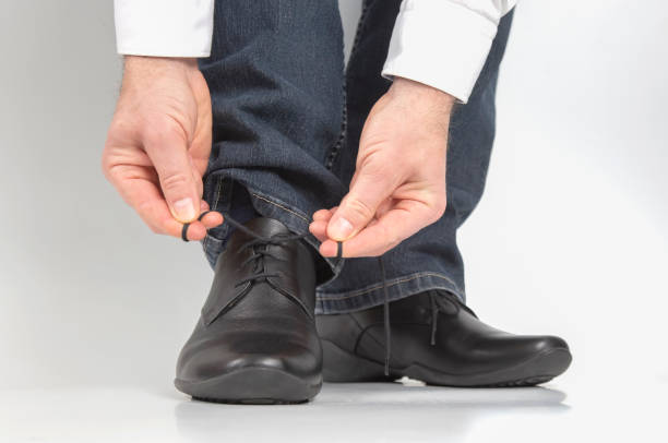 istock Man tying shoelaces on classic black shoes 1144217248