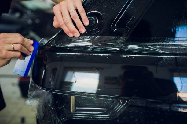 istock Worker hands installs car paint protection film wrap. 1144222936