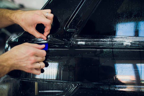 istock Worker hands installs car paint protection film wrap. 1144222937
