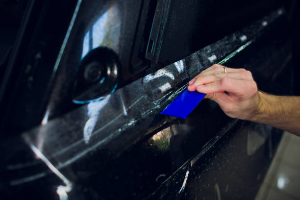 istock Worker hands installs car paint protection film wrap. 1144222938