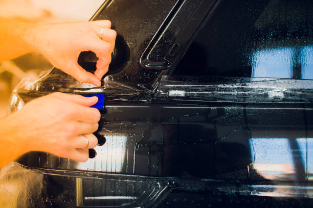 istock Worker hands installs car paint protection film wrap. 1144222940