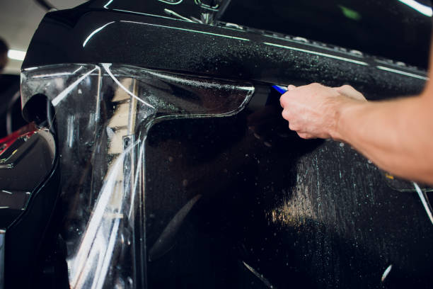 istock Worker hands installs car paint protection film wrap. 1144222949