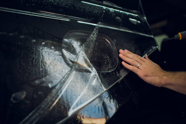istock Worker hands installs car paint protection film wrap. 1144222969