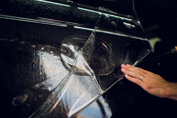 istock Worker hands installs car paint protection film wrap. 1144222976