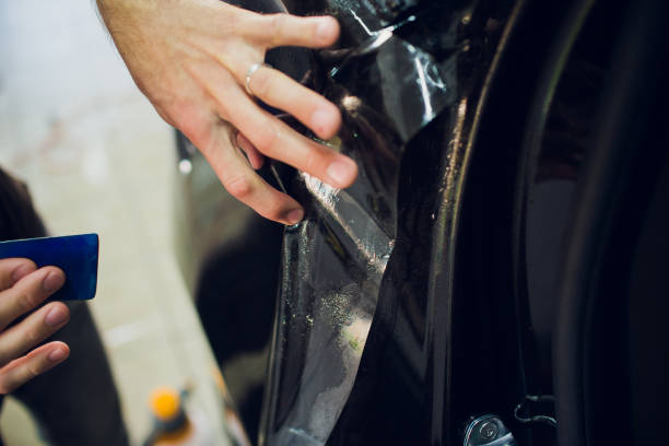 istock Worker hands installs car paint protection film wrap. 1144223018