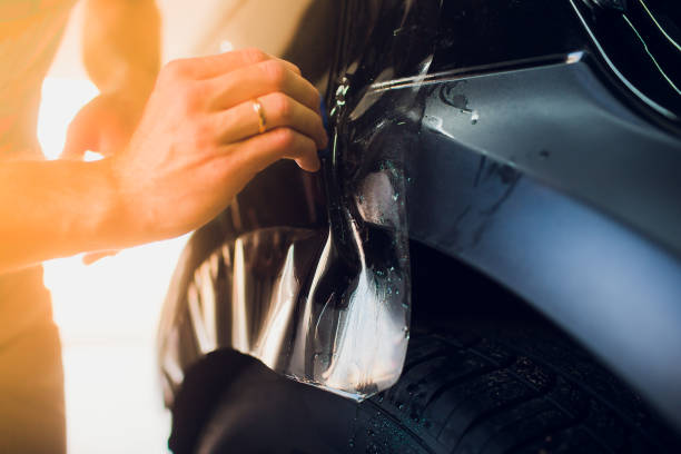 istock Worker hands installs car paint protection film wrap. 1144223024