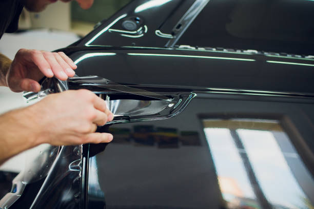 istock Worker hands installs car paint protection film wrap. 1144224239