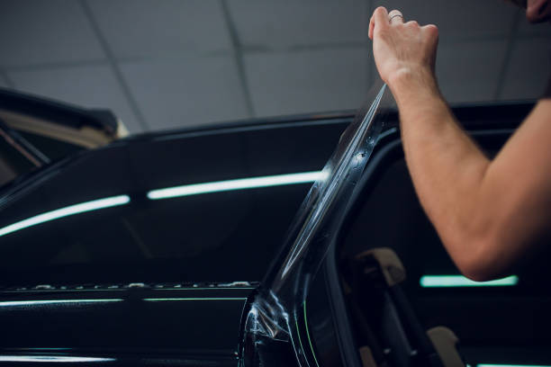 istock Worker hands installs car paint protection film wrap. 1144224242