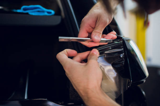istock Worker hands installs car paint protection film wrap. 1144224252