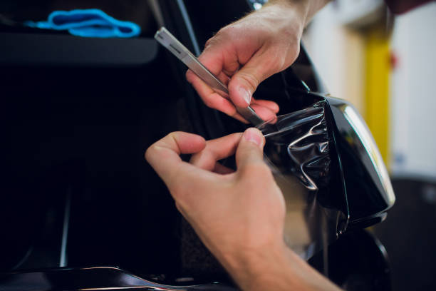 istock Worker hands installs car paint protection film wrap. 1144224254