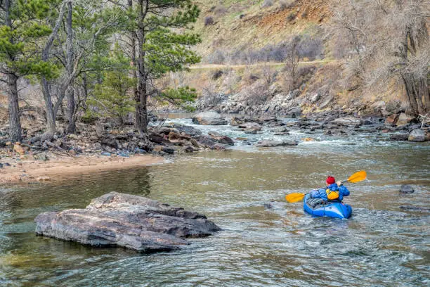 paddler in an inflatable packraft on a mountain river in early spring - Poudre River above Fort Collins, Colorado